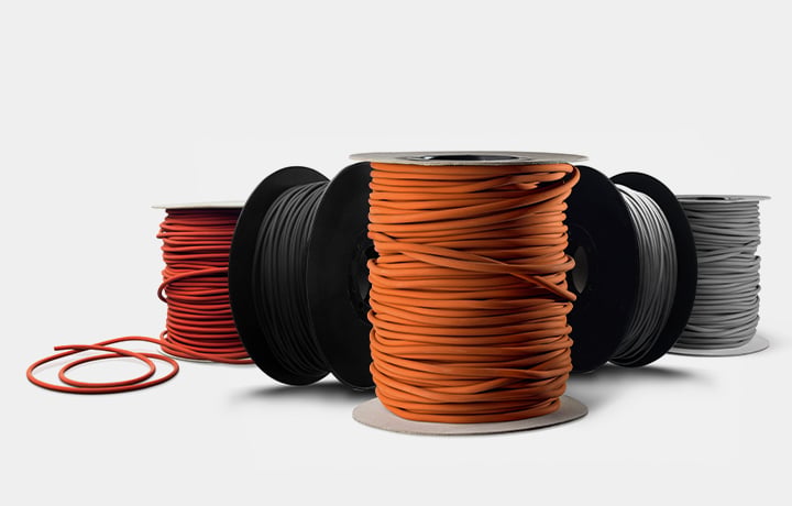 Bobine di corde O-ring in elastomero in diversi colori su sfondo chiaro